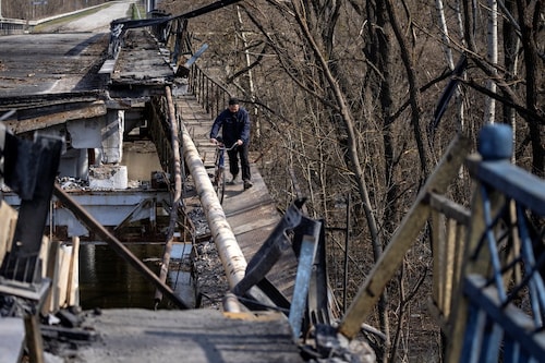 A man crosses a destroyed bridge near the village of Bohorodychne in the Donbass region on April 5, 2022. (Credit: FADEL SENNA / AFP