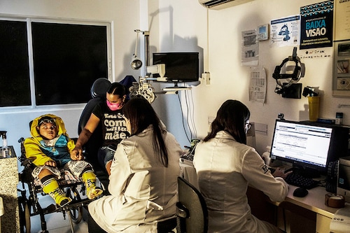 Ana Ipojuca holds the hand of her son Christian, 6, as an opthamologist checks his eyes in Recife, Brazil, June 2, 2022. Some of the babies born with devastating defects by mothers infected with the mosquito-borne Zika virus during a 2015-2016 outbreak are now 7, and families in this scrappy corner of Brazil are struggling to get help for their children, whose mysterious condition constantly presents new challenges. (Dado Galdieri/The New York Times)