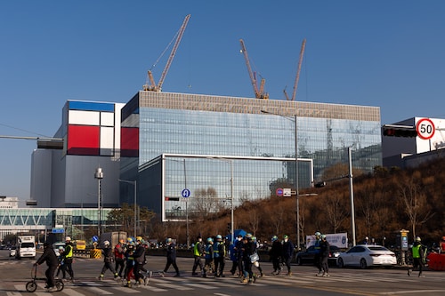 Workers cross a road in front of the Samsung Electronics Co. semiconductor manufacturing plant in Pyeongtaek, Gyeonggi Province, South Korea, on Jan 6, 2022. (Credits: SeongJoon Cho / Bloomberg via Getty Images)