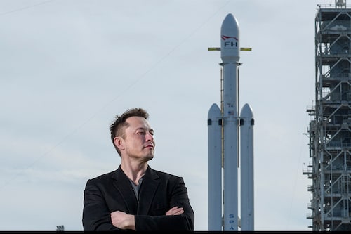 Elon Musk poses with the SpaceX Falcon Heavy rocket, at NASA"s Kennedy Space Center in Cape Canaveral, Fla., Feb. 5, 2018. In emails to workers at SpaceX and Tesla, Musk said workers were required to spend a minimum of 40 hours a week in the office. (Todd Anderson/The New York Times)