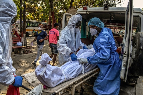 Workers transport the body of a person who died of COVID-19 in New Delhi on April 24, 2021. Nearly a third of excess deaths globally, some 4.7 million, took place in India. (Atul Loke/The New York Times)