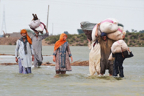 Villagers carrying animal feed wade through flood waters following monsoon rainfalls in Jaffarabad district in Balochistan province on August 24, 2022. - Record monsoon rains were causing a "catastrophe of epic scale", Pakistan"s Climate Change Minister said August 24, announcing an international appeal for help in dealing with floods that have killed more than 800 people since June. Image: Fida Hussain / AFP