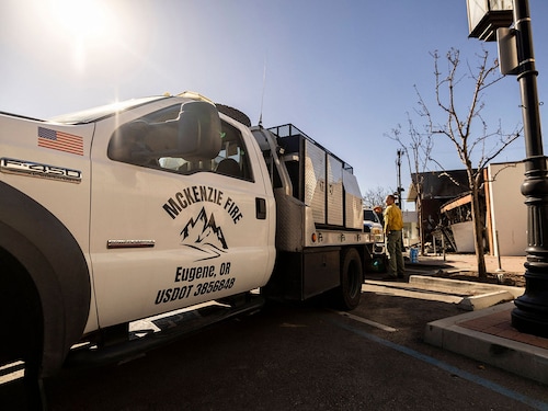 A private firefighting company employee, hired to protect Rick Caruso"s Palisades Village mall from the Palisades Fire, stands near a vehicle at the mall in Pacific Palisades. 
Image: Etienne Laurent / AFPÂ©