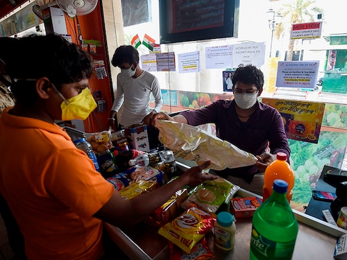 An employee (R) wearing a facemask as a preventive measure against the COVID-19 novel coronavirus attends to a customer at a grocery store in Faridabad on March 23, 2020. (Photo by Money SHARMA / AFP) (Photo by MONEY SHARMA/AFP via Getty Images)