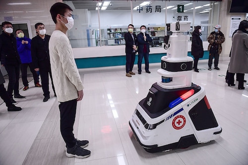 This photo taken on February 26, 2020 shows a patrol robot - used to check temperatures, identities and disinfect people - checking the temperature of a visitor at a hospital in Shenyang in China's northeastern Liaoning province. The hospital uses the robot to reduce the pressure on front-line medical staff and to avoid cross infections from the COVID-19. Image: STR/AFP via Getty Images