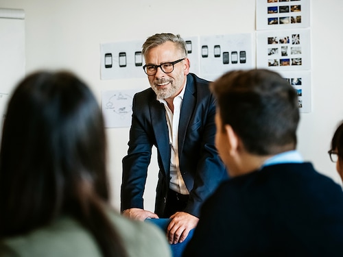 Mature businessman speaking during an informal meeting to younger colleagues Mature businessman speaking during an informal meeting to younger colleagues