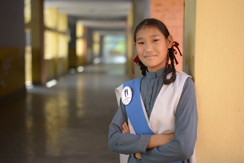 An Adolescent Peer Educator stands proudly after attending her orientation and training