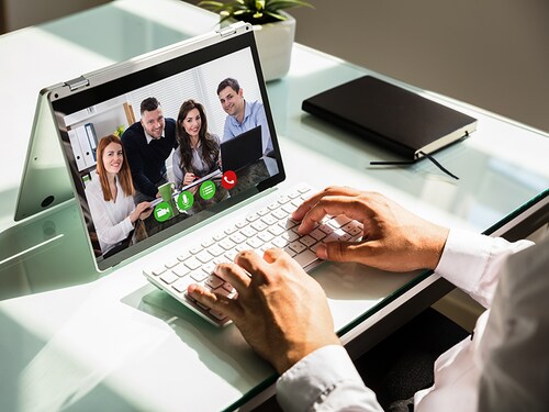 Businessman's hand video conferencing with his colleagues on laptop
