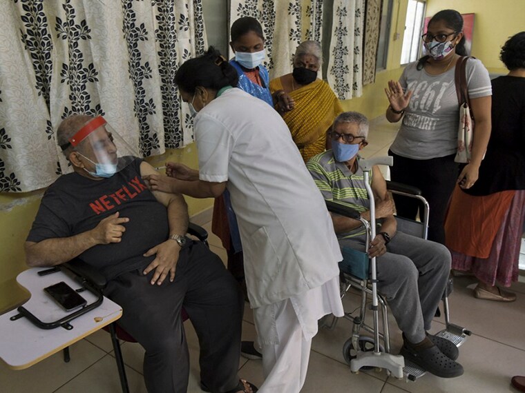 A health worker (2L) inoculates a senior citizen with a Covid-19 coronavirus vaccine at a government hospital in Bangalore on March 5, 2021 as India continues its vaccination programme for people above 45 year-old with co-morbidities and for those above 60 year-old. (Photo by Manjunath Kiran / AFP)