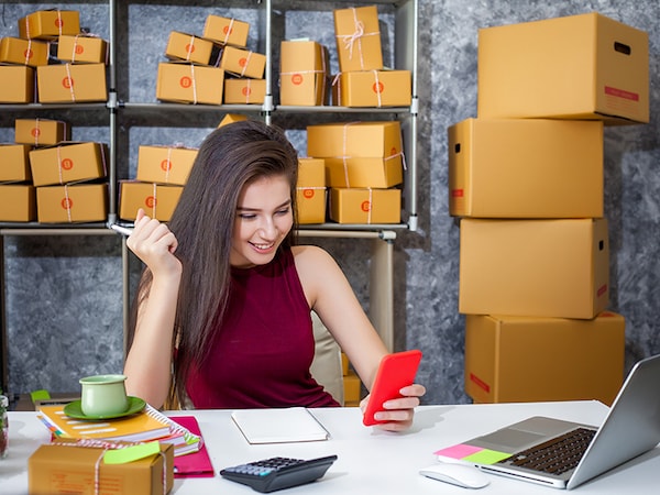 Young woman entrepreneur selling online product and mobile phone sitting smile happily in her workplace.