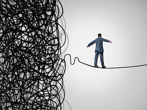 Crisis Management business concept as a tightrope walker walking out of a confused tangled chaos of wires breaking free to a clear path of risk opportunity as a metaphor for managing organizations.