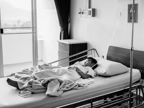 Patients lying on a bed in a hospital room.
