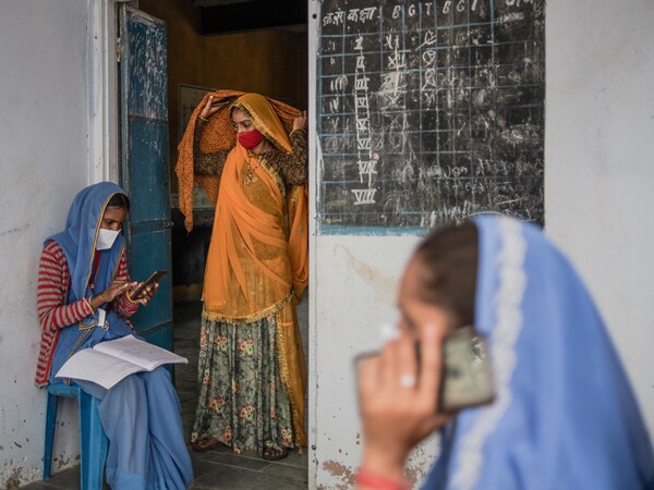 AAKHTADI, INDIA - MAY 17: Indian accredited social health activist (ASHA) Samodra Verma (L), 32, welfare worker Parvati Regar (C), 18, and ASHA worker Geeta Chaudry, 39, call and register vaccine beneficiaries ahead of the start of vaccination clinic to administer the Covaxin coronavirus vaccine amid Rajasthan's ongoing coronavirus lockdown on May 17, 2021 in Aakhtadi, Tonk District, Rajasthan, India. India's prolonged and devastating wave of Covid-19 infections has gripped cities and overwhelmed urban health resources, but it has also reached deep into rural India, where the true extent of devastation is unknown because of the lack of widespread testing or reliable data. (Photo by Rebecca Conway/Getty Images)