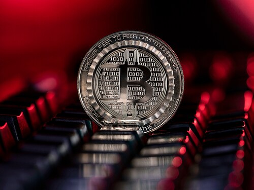 Bitcoin BTC cryptocurrency physical coin placed on the computer keyboard and lit with red light.