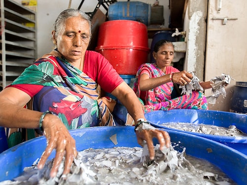 AHMEDABAD, INDIA: 
At a modular roof factory workers Umja Ambalal (right) and Praba Maya work with recycled cardboard,soaking it in water and then putting it in a machine which grinds it up.
Using roofs from waste paper for slum houses. The women get 275 ruppies per day, SEWA helped trained them to operate machinery. (Photo by Paula Bronstein/Getty Images)