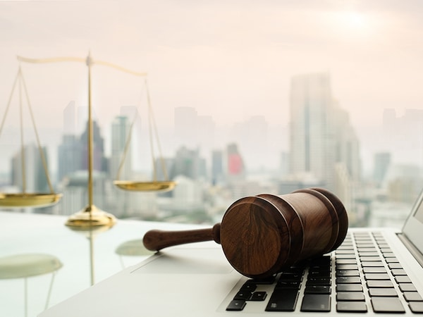 law legal technology concept.  judge gavel on computer with scales of justice on desk of lawyer.