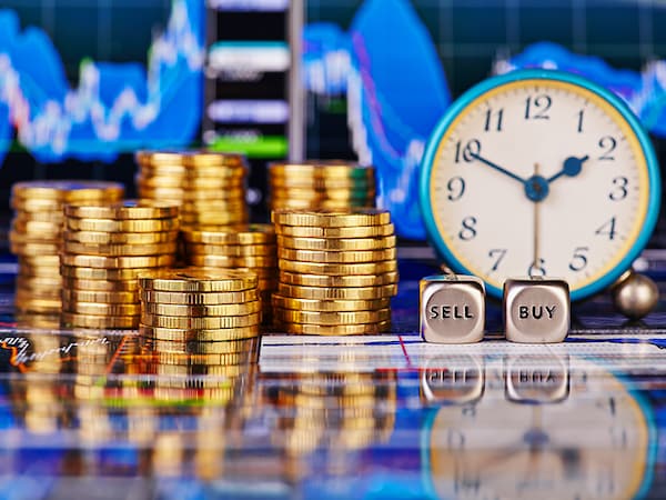 Stacks of golden coins, clock, dices cubes with the words SELL BUY. The financial chart as background. Selective focus