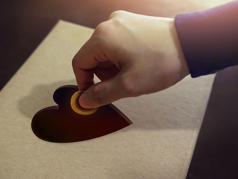 Donation Concept. Hand putting Money Coin into a Heart Shape hole on Donate Box