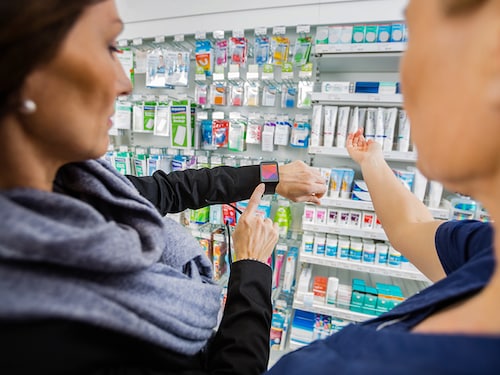 Mid adult female customer showing smartwatch to pharmacist in drugstore