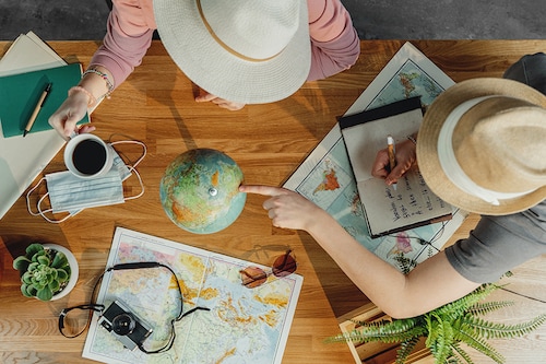 Top view of young couple with maps planning vacation trip holiday, desktop travel concept.