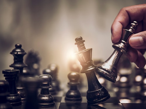 hand of businessman moving chess figure in competition success play. strategy, management or leadership concept