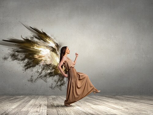 Attractive woman with angel wings in empty room
