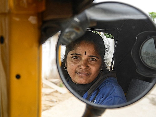 Indian auto rickshaw driver Vennapusa Narayanamma poses in her vehicle as she waits for passengers in the Bachupally District on the outskirts of Hyderabad on August 3, 2014. Thirty six year old Narayanamma, who earns between Indian Rupees 300-400 (USD 4.90-6.55) per day,  is an un-educated, mother of two children, She has been driving  her vehicle which she purchased with the assistance of an NGO  for the last five years, and it provides a means to supplement her family income as well as a safe mode of transport for the working  women of her community.   AFP PHOTO/NOAH SEELAM (Photo by NOAH SEELAM / AFP)