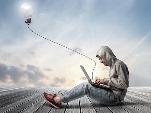 Man using a laptop with light bulb plugged in it