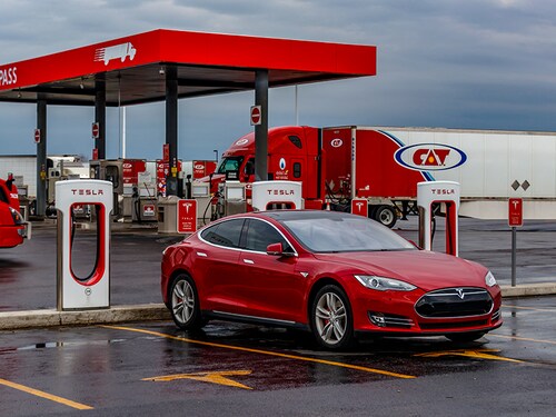 COMBER, CANADA - April 16, 2019: Tesla Supercharger Station with red Tesla Model S plugged-in, charging and truck stop in the background.
