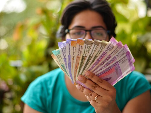 An Indian women holding all the colorful new released Indian Rupees currency notes after demonetisation in denominations 10,50,100, 200, 500, 2000 in her hands with her blur face in the background