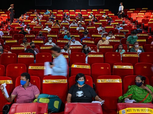 People sit inside an auditorium as they wait to get inoculated with a dose of the Covishield vaccine against the Covid-19 coronavirus, at a temporary vaccination centre set up inside a multiplex cinema hall complex in Mumbai on August 17, 2021. (Photo by Punit PARANJPE / AFP) (Photo by PUNIT PARANJPE/AFP via Getty Images)