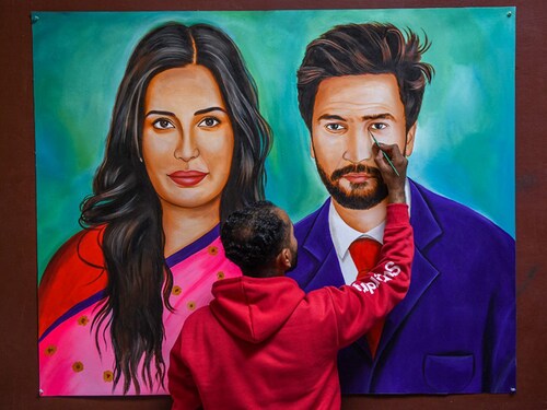 An artist gives final touches to an oil painting of Indian Bollywood actors Vicky Kaushal and Katrina Kaif in his studio in Amritsar on December 9, 2021 which he plans to send as a wedding present to the couple. (Photo by NARINDER NANU / AFP)