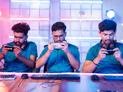 Front view of Team of young professional gamers seriously playing of live video game on mobile phone at esports tournament