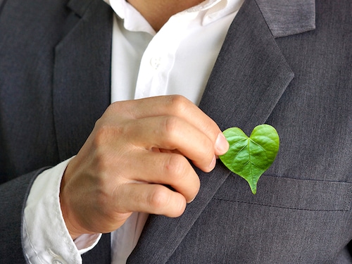 Businessman holding a green heart leaf / Business with corporate social responsibility and environmental concern