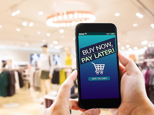 BNPL Buy now pay later online shopping concept.Hands holding mobile phone on blurred store as background