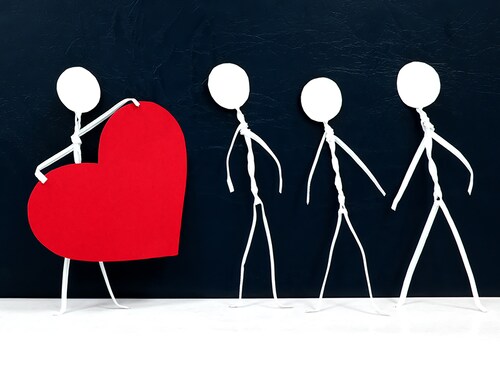 Human stick figure holding a big red heart in dark background. Help, spread love, charity and kindness at times of darkness concept.