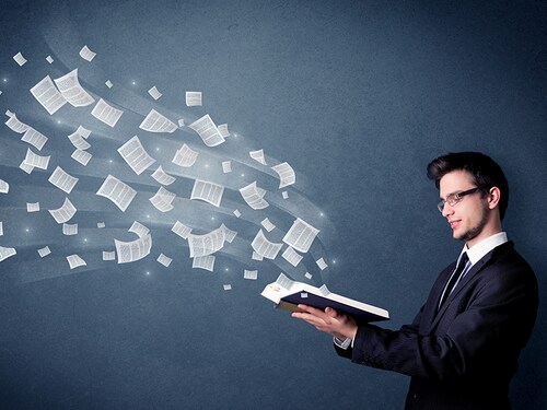 Casual young man holding book with pages flying out of it