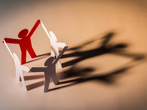 closed joining of four paper figure in hand up posture on light background. in concept of cooperation, successful and leadership.