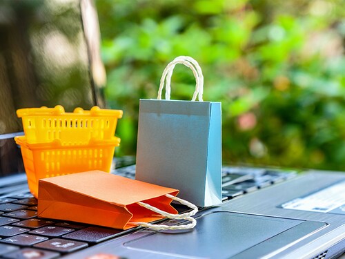 Online shopping and ecommerce over internet concept : Paper shopping bags, shopping baskets on a laptop computer, depicts consumers always buy gadget, goods or things directly from online retail store