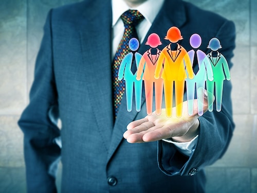 White collar manager presenting a work team of five multicolored worker icons in open palm of his left hand. Business concept for team building, diversity inclusion culture and staffing solutions.
