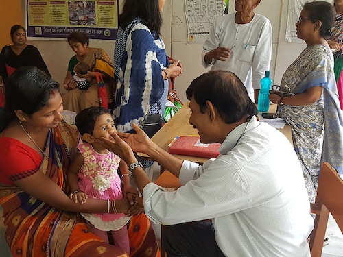 Kolkata, India - Sep 06,18: A doctor sitting in the clinic for poor checking the childs tonsils.