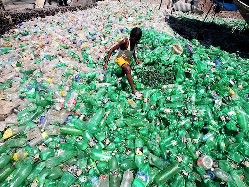 A boy walks through a plastic junkyard in Togga village of the northern Indian state of Punjab May 11, 2010. Emissions rose to 1.9 billion tonnes in 2007 versus 1.2 billion in 1994, with the industrial and transport sectors upping their share in Asia's third largest economy and confirming India's ranking among the world's top five carbon polluters. REUTERS/Ajay Verma (INDIA - Tags: ENVIRONMENT BUSINESS TRANSPORT) - GM1E65B1GE101