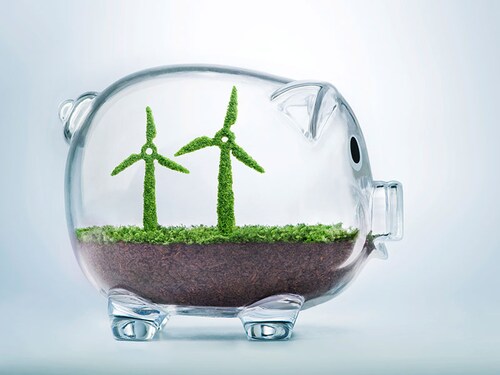 Grass growing in the shape of two wind turbines, inside a transparent piggy bank, symbolising the need to invest in the protection of the environment and to reconnect with nature.