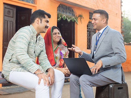 Real estate agent or financial advisor with laptop meeting rural Indian couple, Male bank manager discussing with traditional asian family. low angle