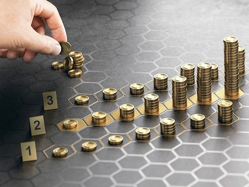 Human hand stacking coins over a black background with hexagonal golden shapes. Concept of investment management and portfolio diversification. Composite image between a hand photography and a 3D back