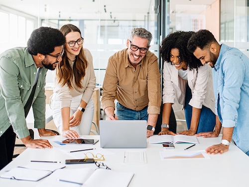A panoramic view of a motivated team intensely focused on a computer screen, capturing the essence of a strategic work session in a contemporary, light-filled office. Diverse work group brainstorming