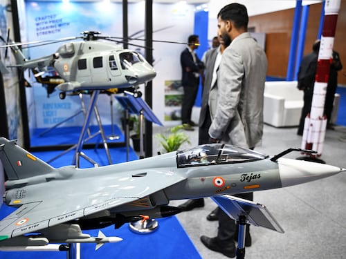 Visitors walk past "Tejas light combat aircraft" model displayed during AeroDefCon 2025, at the trade center in Chennai on October 7, 2025.