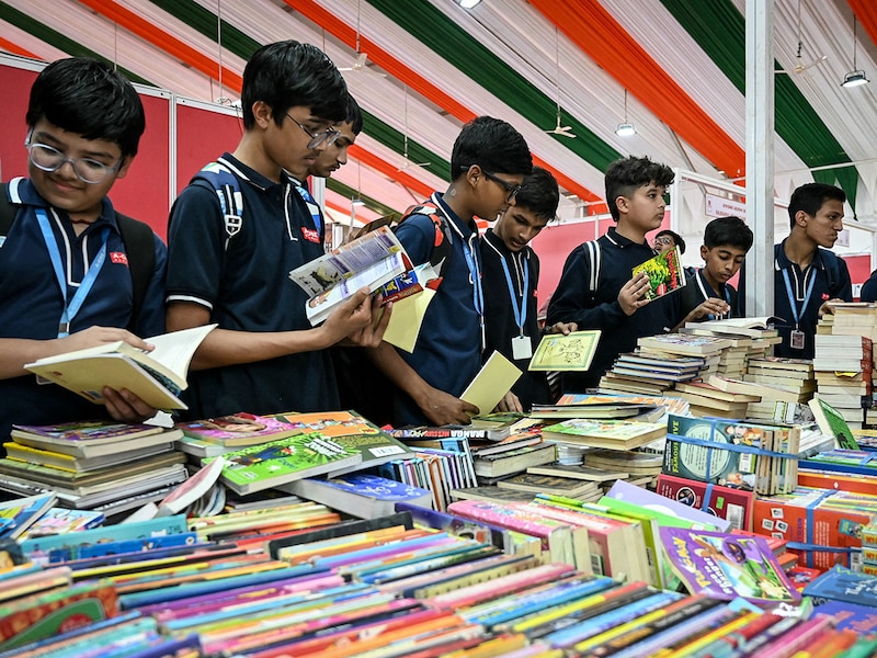 Students check books during their visit to the International Book Fair at Sabarmati River Front in Ahmedabad on November 13, 2025.