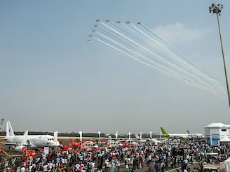 Visitors watch the Indian Air Force's Surya Kiran aerobatics team performing during an air show at the Begumpet Airport in Hyderabad on January 30, 2026.