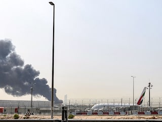 : An Emirates aircraft prepares for landing as a smoke plume rises from an ongoing fire near Dubai International Airport in Dubai on March 16, 2026. Flights were gradually resuming at Dubai airport on March 16, previously the world's busiest for international flights, the airport operator said, after a "drone-related incident" sparked a fuel tank fire nearby, as Iran kept up its Gulf attacks.  Photo by AFP